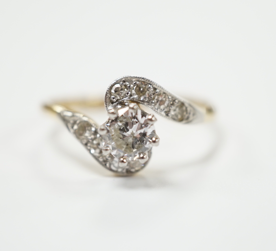 An 18ct, plat and single stone diamond set ring, with diamond chip set crossover shoulders, size P/Q, gross weight 3.1 grams.